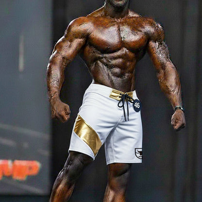 White MetroMaleWear Physique board shorts with gold diagonal stripe, gold belt loop, black drawstring, and logo patch