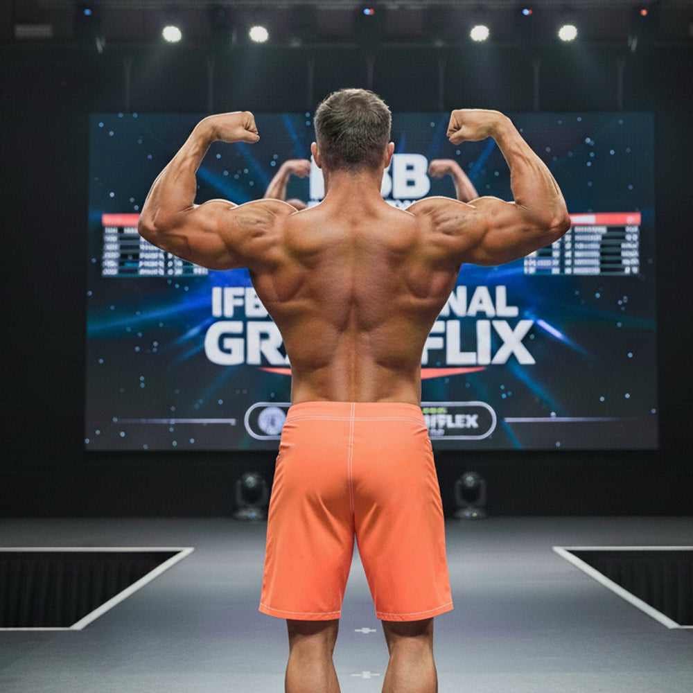 A muscular man showing defined back muscles wears metroMalewear physique board short neon orange on stage back view