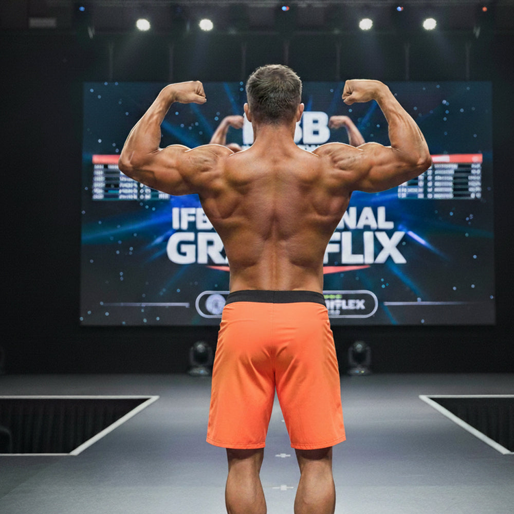 A muscular man showcases the back of metro malewear physique board short orange-black with a black waistband