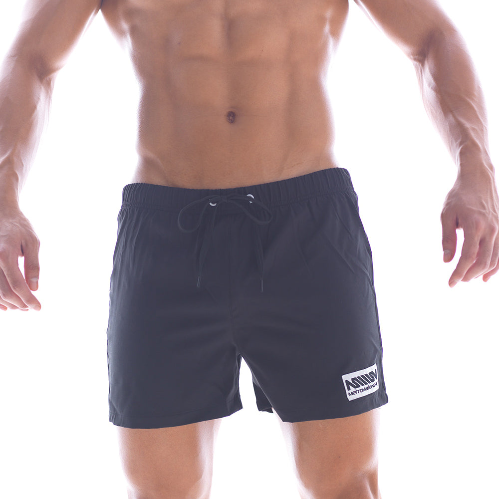 Black athletic swim shorts with drawstring waistband and white logo patch on lower right leg by metromalewear