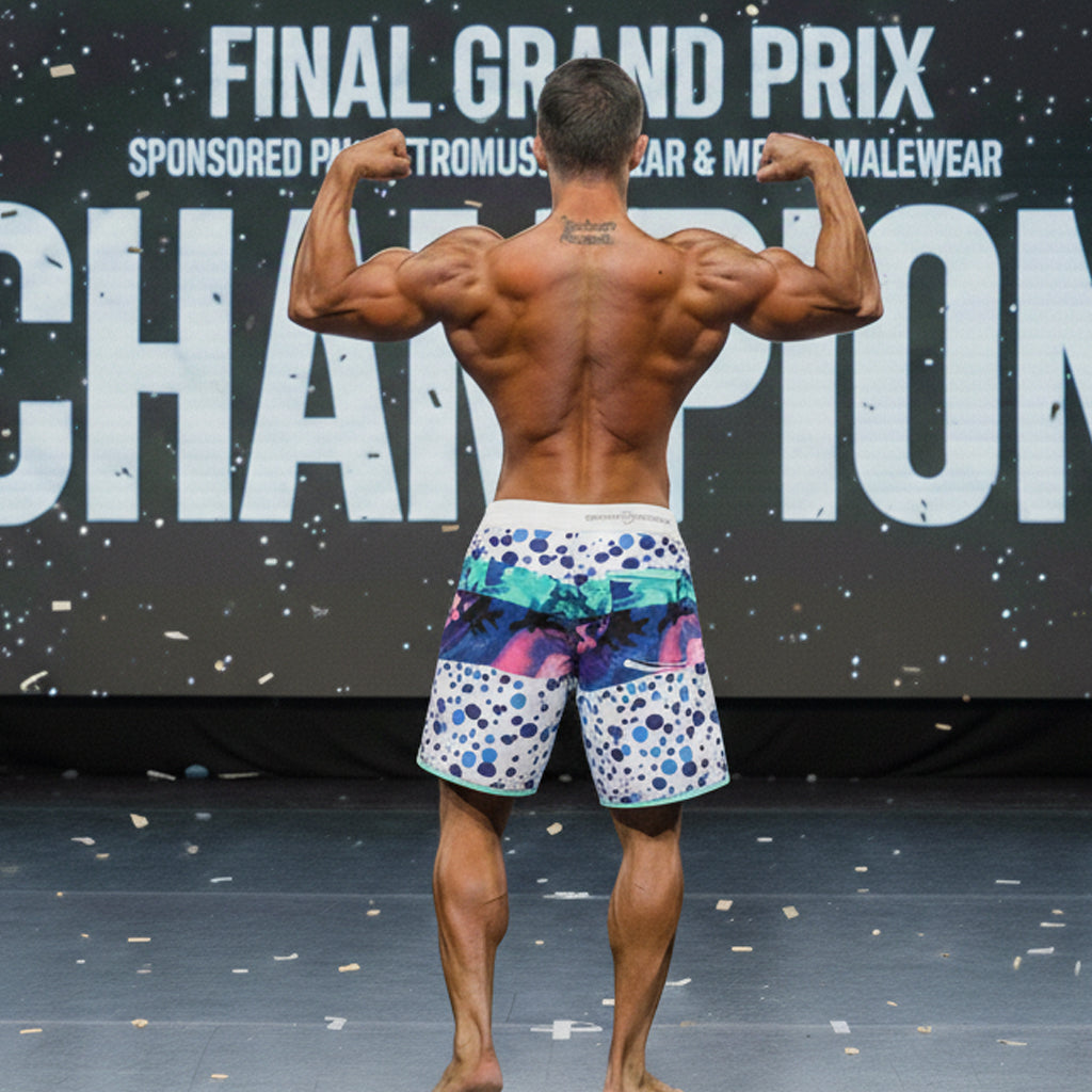 A man wearing MetroMaleWear MetroMuscleWear bubble physique board shorts with vibrant blue pink and teal patterns