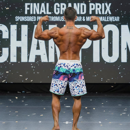 A man wearing MetroMaleWear MetroMuscleWear bubble physique board shorts with vibrant blue pink and teal patterns