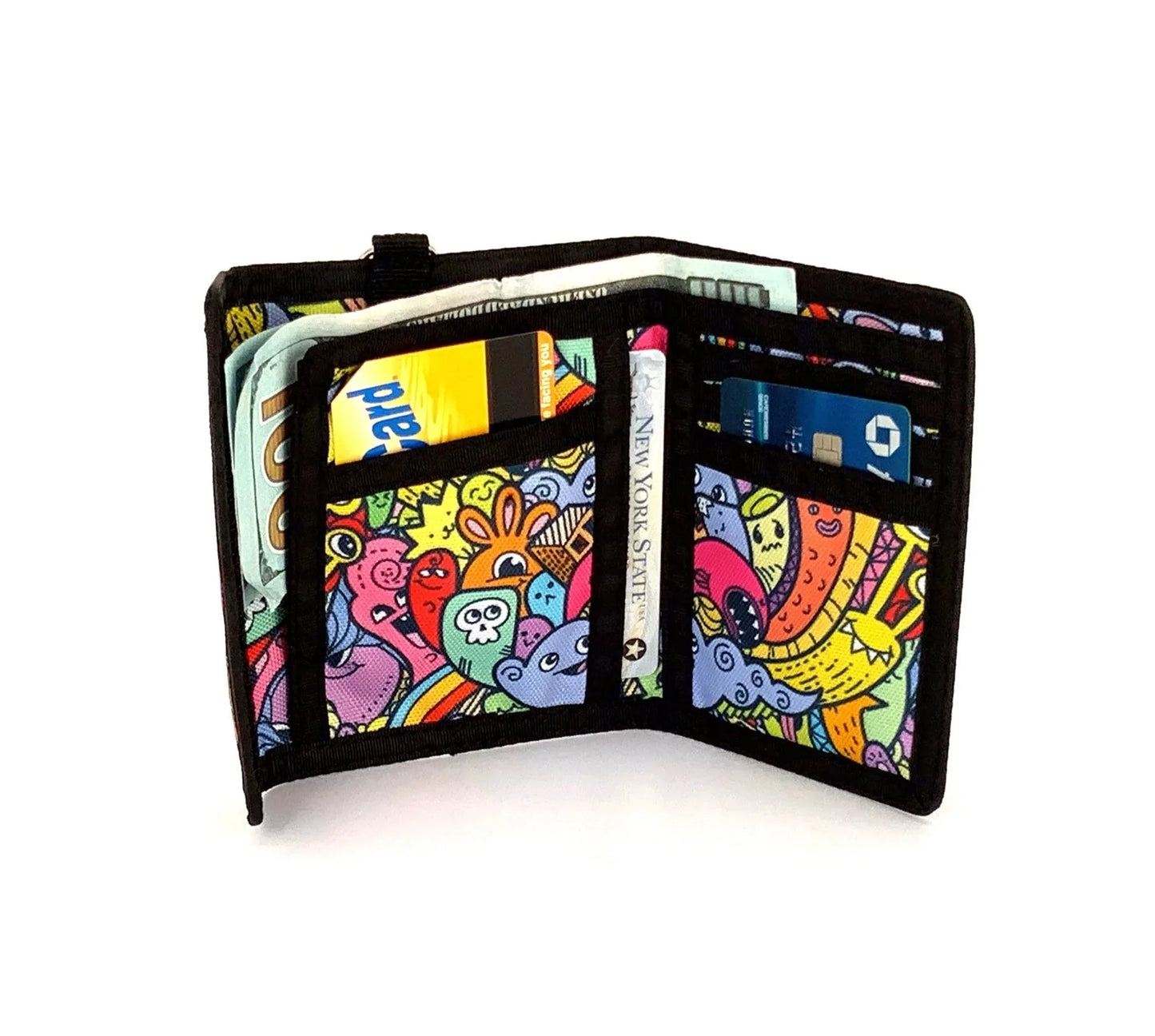 A vibrant 80s velcro tri fold wallet with black trim and colorful cartoon creatures in bold outlines