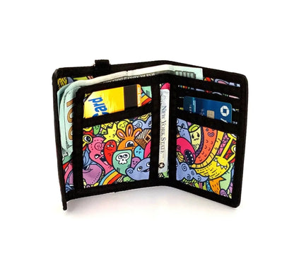 A vibrant 80s velcro tri fold wallet with black trim and colorful cartoon creatures in bold outlines