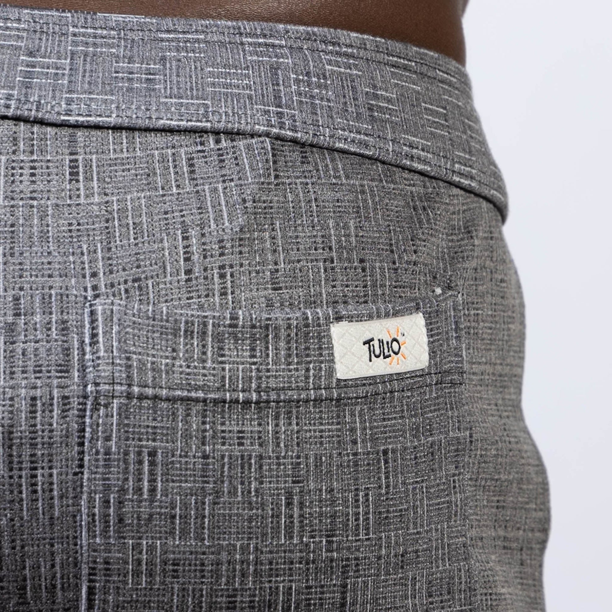 Back side of gray abstract linen texture shorts with subtle geometric pattern and white tulio brand label on pocket