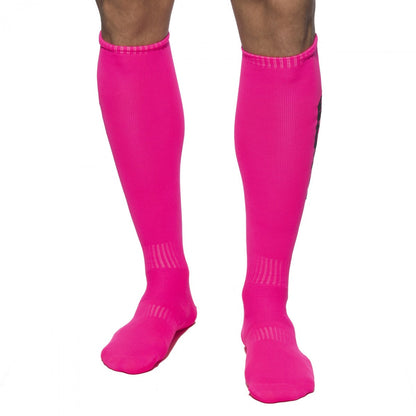 Bright pink addicted neon knee-high athletic socks with ribbed texture and subtle black branding on the side