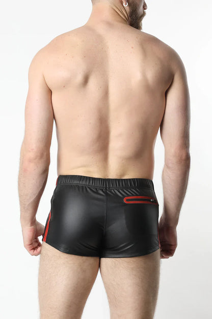 Black shiny faux leather anti-chrome gear shorts with red side stripes and back zipper pocket shown from the back