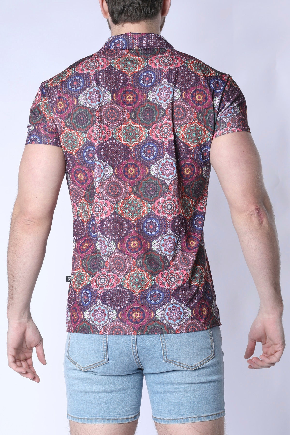 A man wearing a balboa button down shirt with a colorful purple pink and green mandala pattern on dark maroon fabric