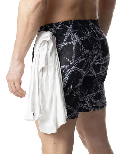 Black barbed wire rugby short swim trunks with bold white pattern and white towel tied around the waist