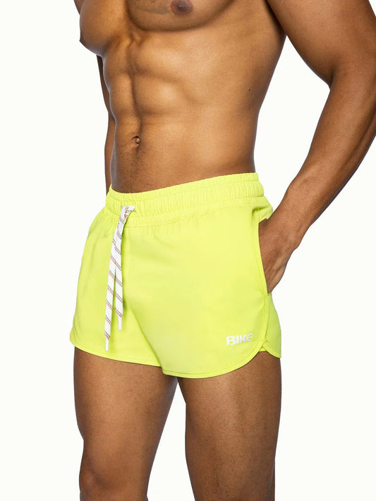 Bike track short in bright neon yellow with white striped drawstring and subtle logo on lower right leg
