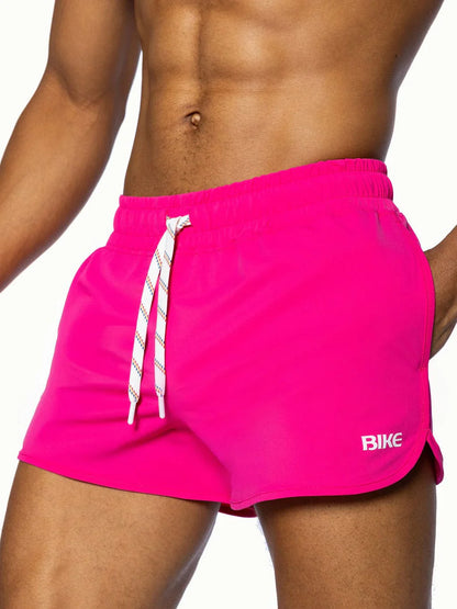 Bright pink bike track short with white drawstrings and bike logo designed for athletic use