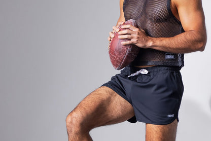 A worn reddish-brown american football with scuff marks and textured surface shown with bike athletic bam200 black track short