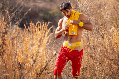 A man outdoors wearing a yellow BIKE Athletic BAS306 original number 10 jockstrap with a small white logo