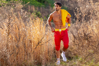 A muscular man wearing BIKE athletic BAS306 original number 10 yellow jockstrap with red shorts and white sneakers