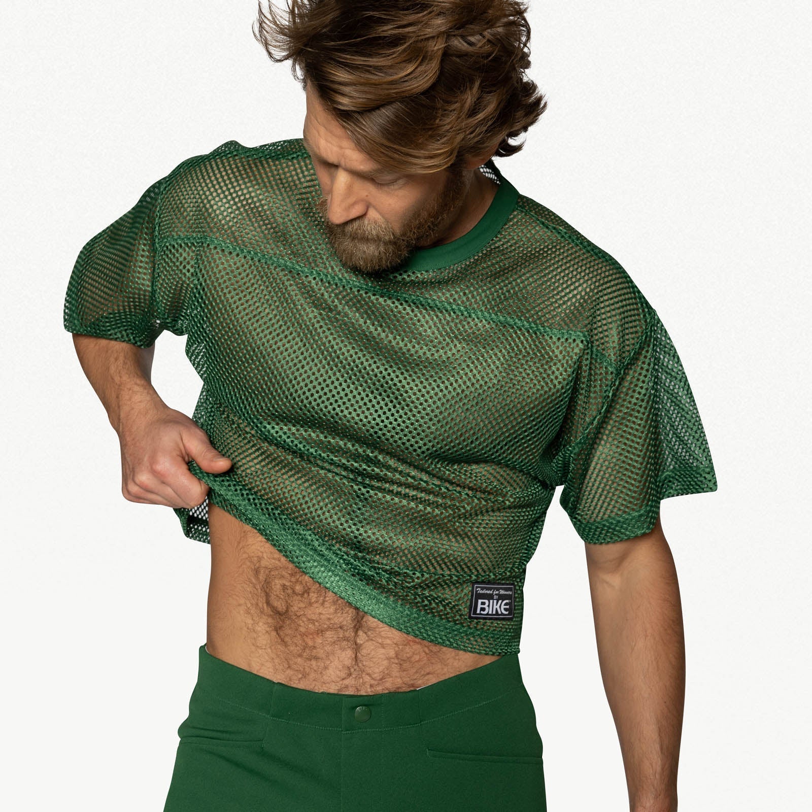 A person wearing a short-sleeve green mesh practice jersey with a small white BIKE logo patch on the lower left.