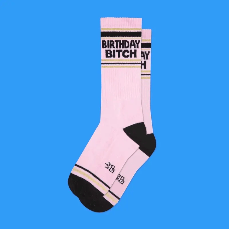 Pink birthday bitch crew socks with black toe and heel and gold striped ribbed cuff featuring bold text
