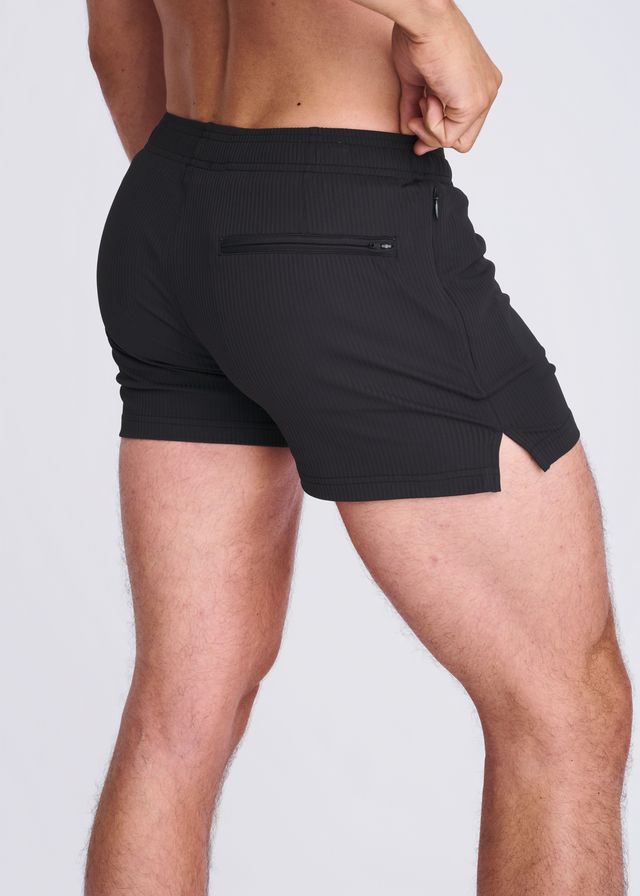 Back view of black seersucker swim shorts with mesh lining featuring a zippered back pocket and side slit
