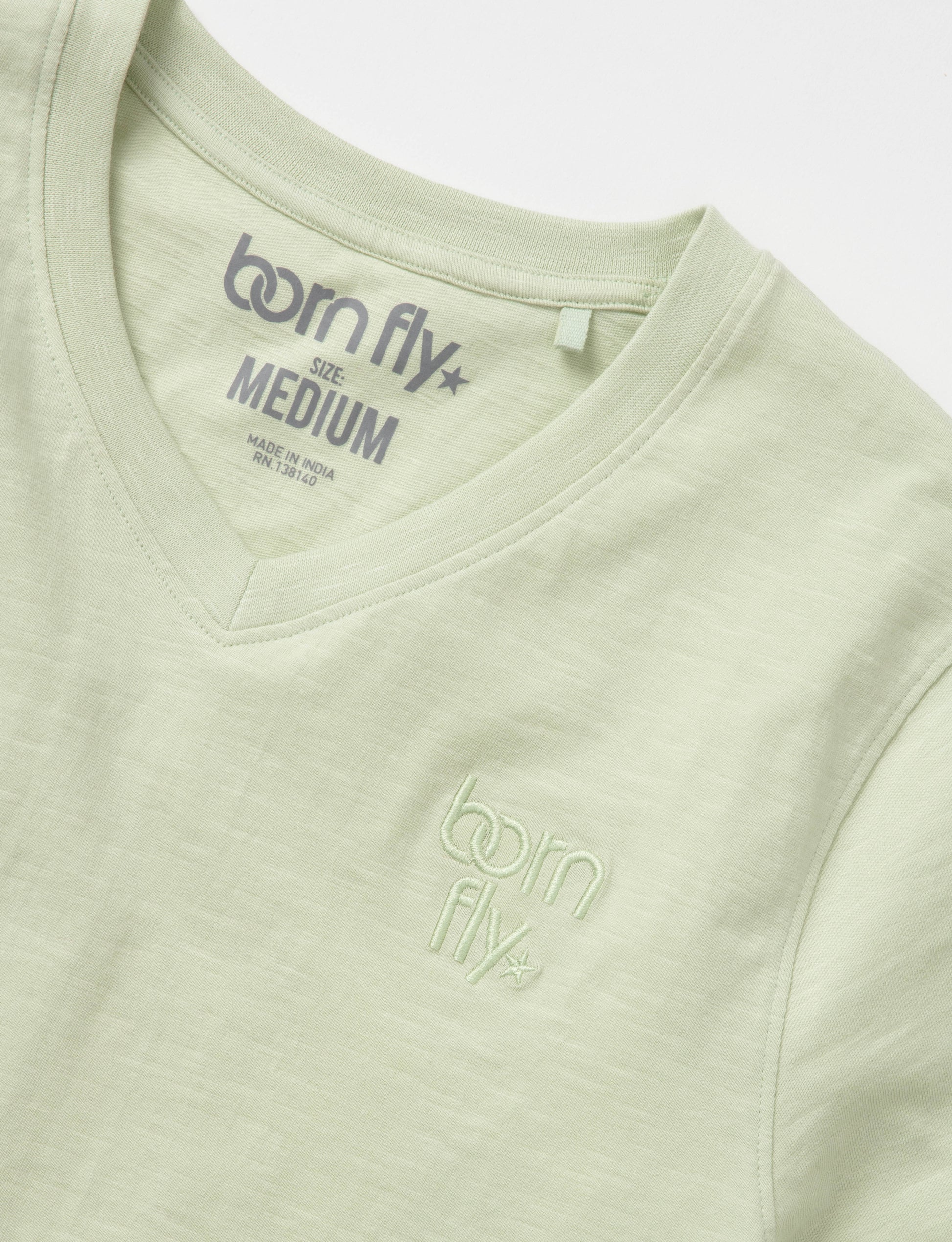 A light green cotton born fly v-neck tee with subtle embroidered logo on the chest and matching inside collar tag