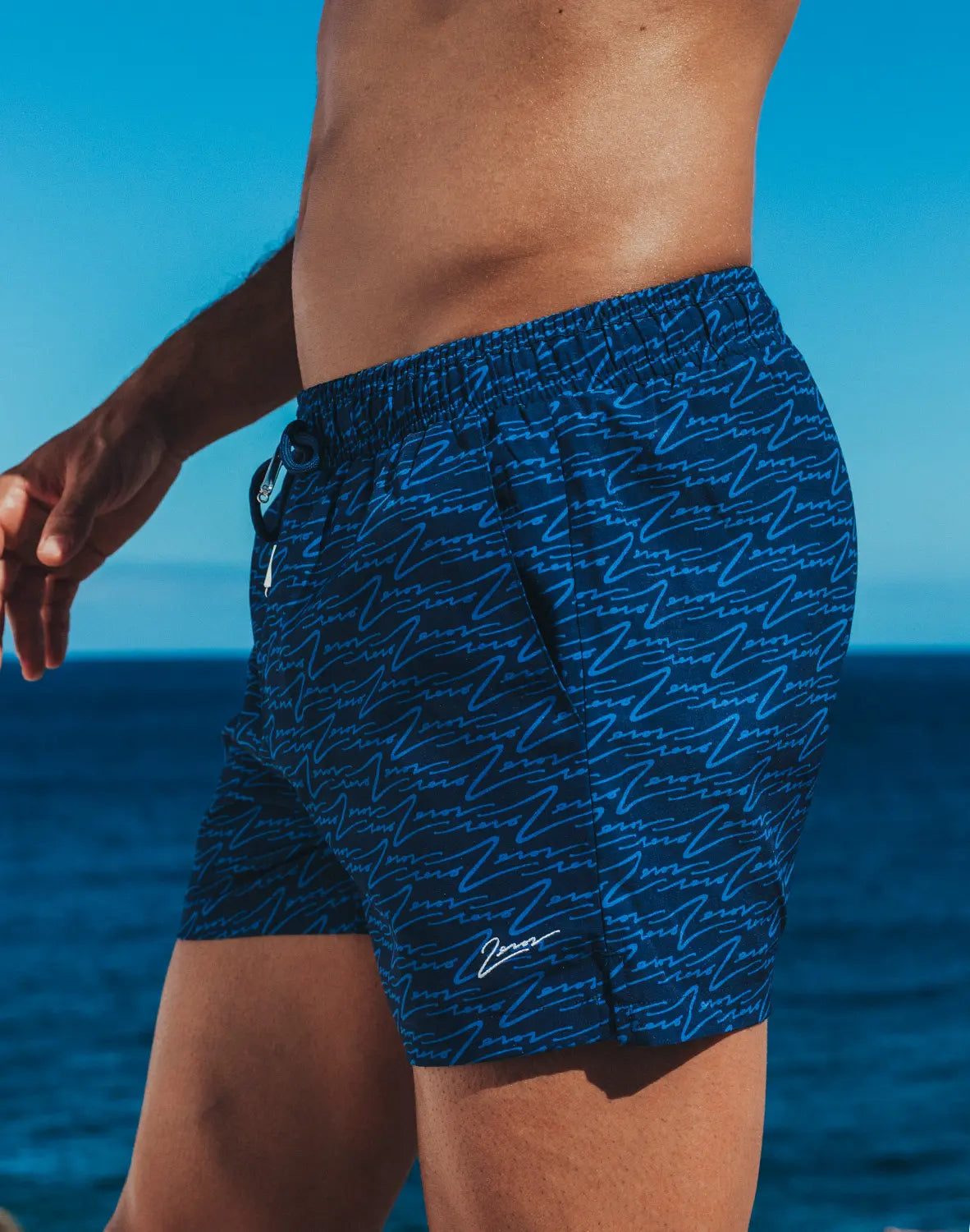 Dark blue byron swim short featuring light blue abstract wave pattern and small white signature logo on lower right leg