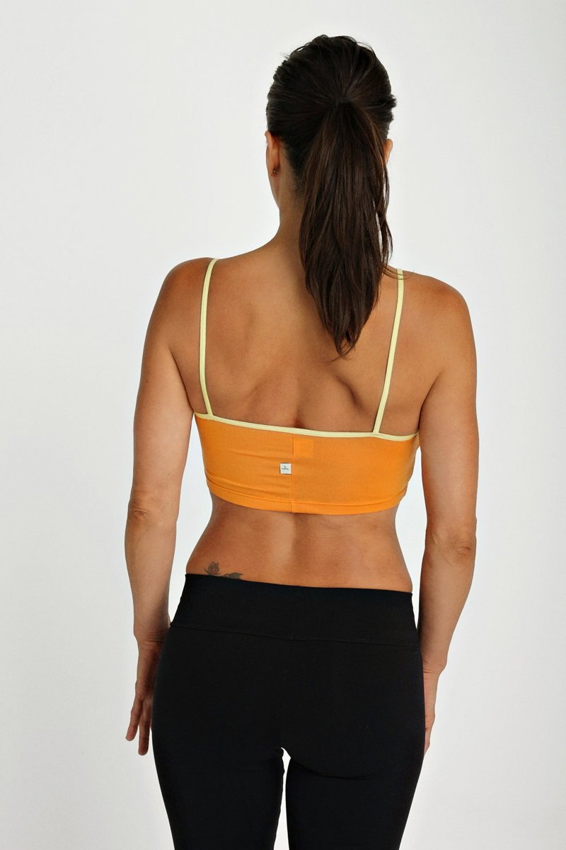 Back view of orange bra top tangerine with pale yellow straps and small white logo designed for activewear