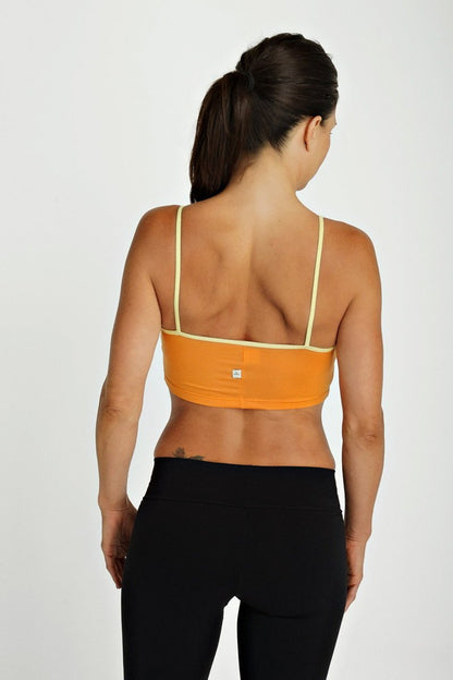 Orange sports bra top tangerine with thin yellow straps and a small brand logo visible on the back side
