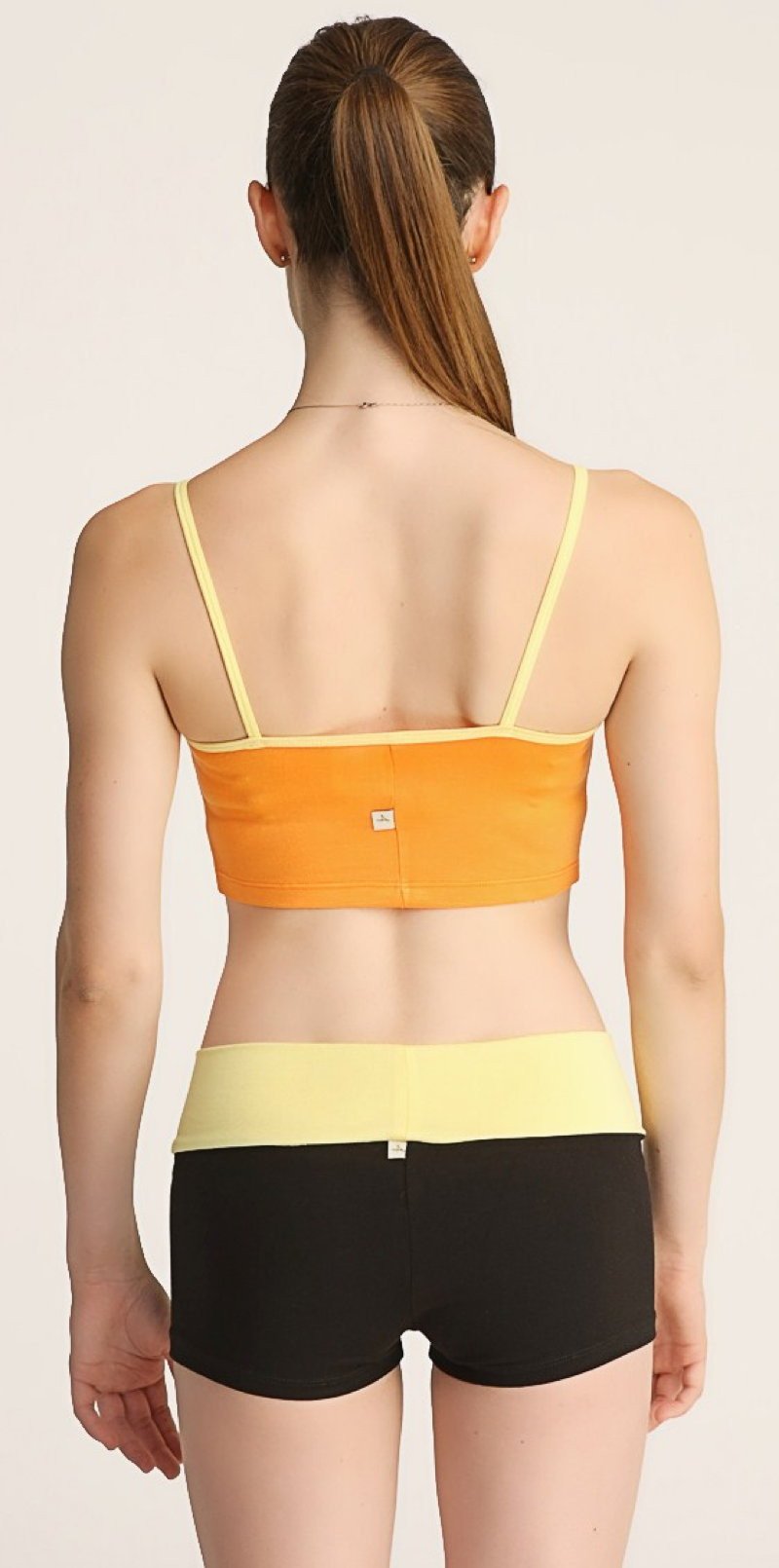 Orange and yellow strap sports bra paired with black bumble short shorts for activewear use