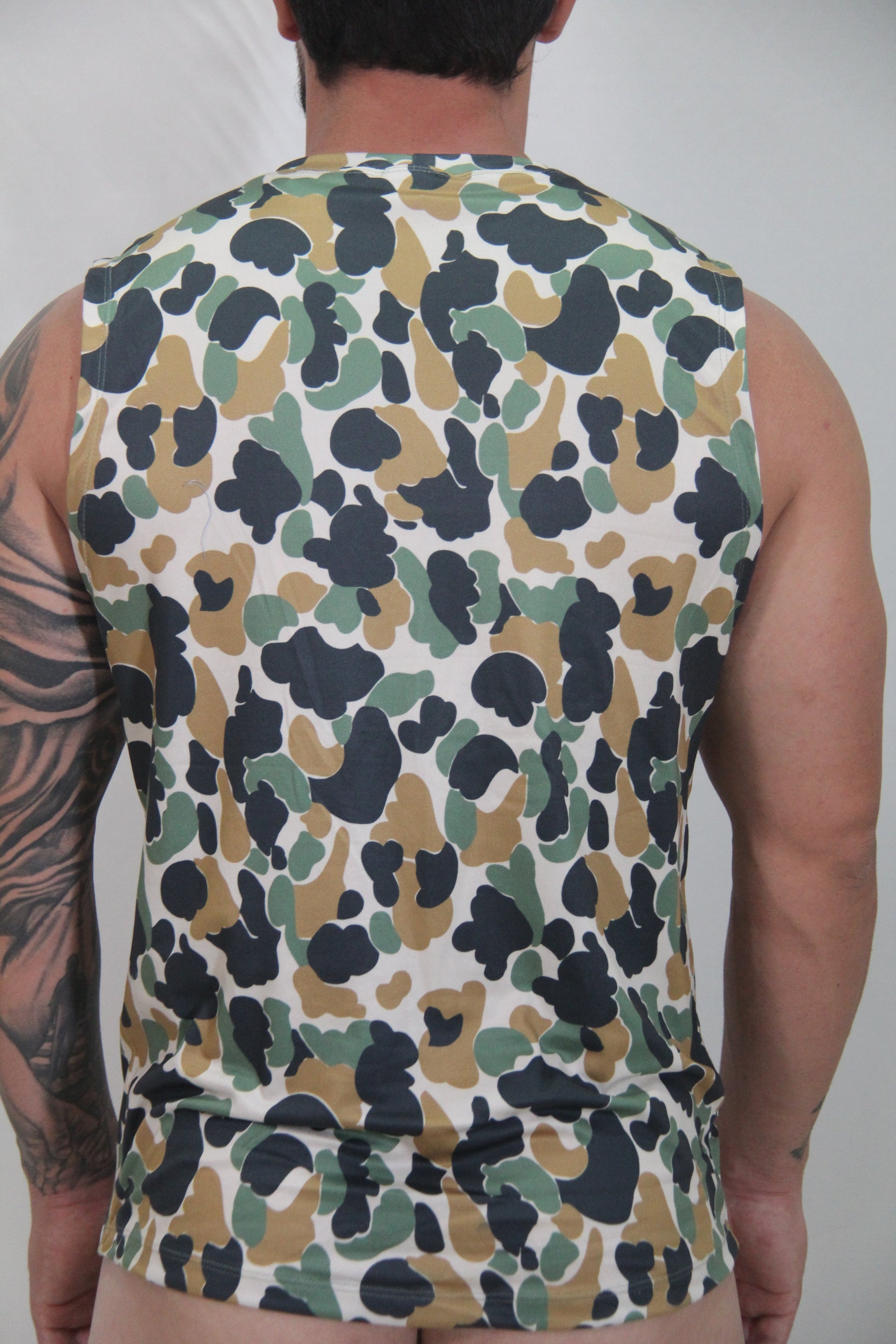 Camouflage open arm tank is a sleeveless top with olive green tan and black splotches on a white base