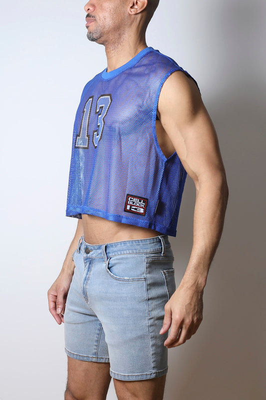 A person wears a blue mesh crop top with the number 13 on the chest.