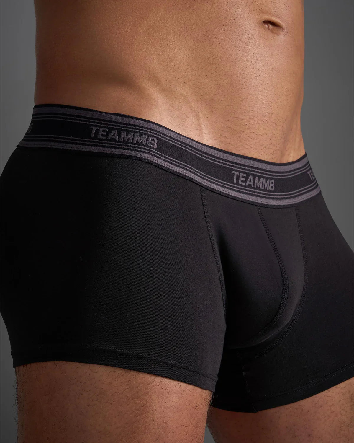 Black classic cotton trunk briefs with gray elastic waistband and white brand name lettering on front side