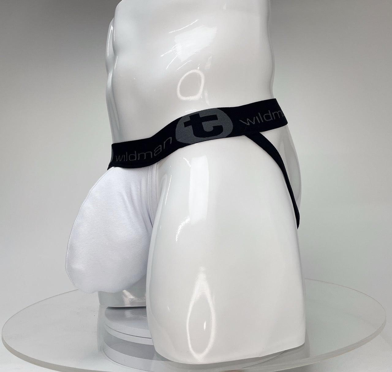 White jockstrap with a large pouch on a white mannequin, featuring a black branded waistband with a WildmanT logo.