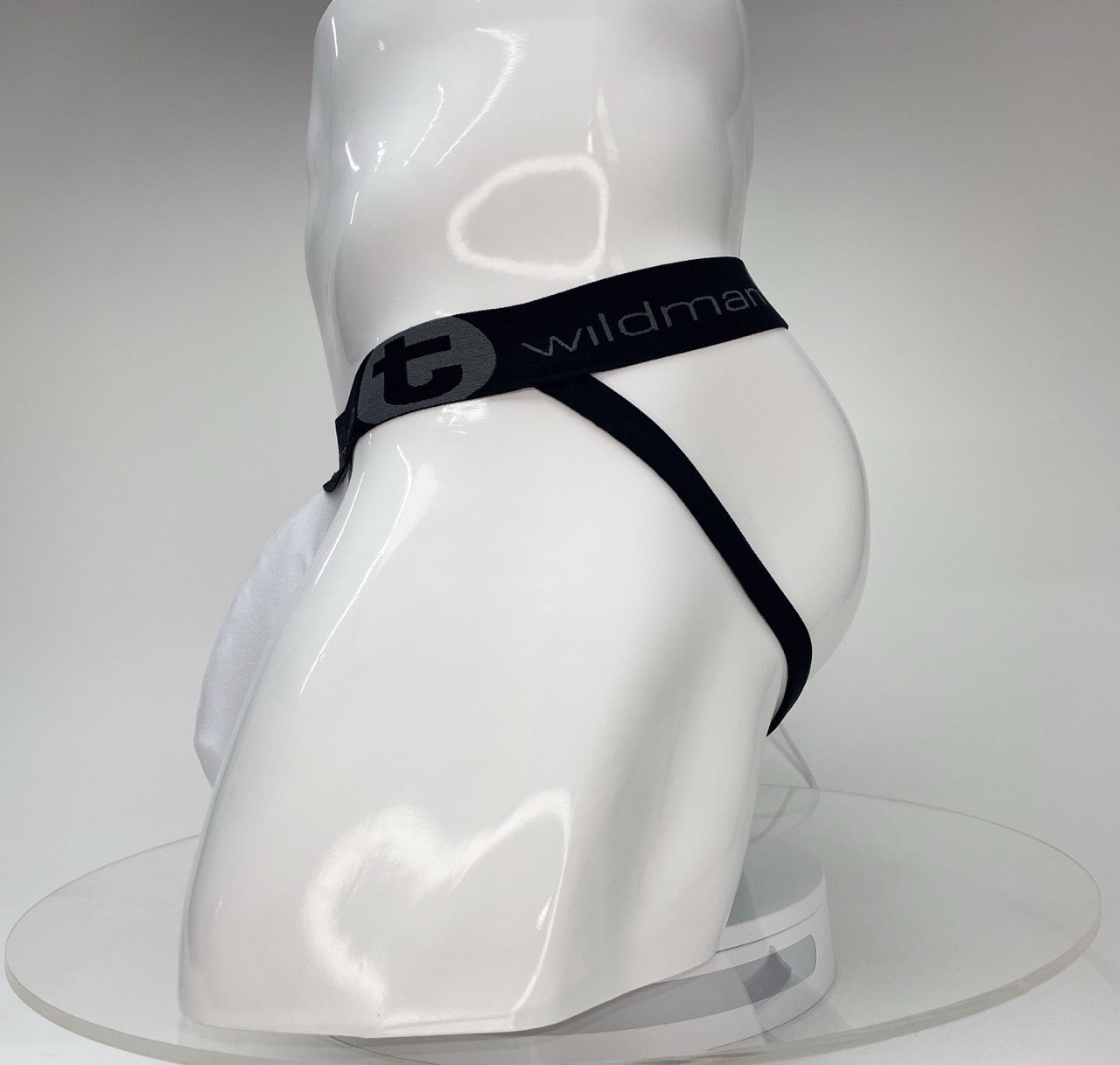 White WildmanT Big Boy pouch jockstrap on a mannequin, featuring a black branded waistband with a circular logo.