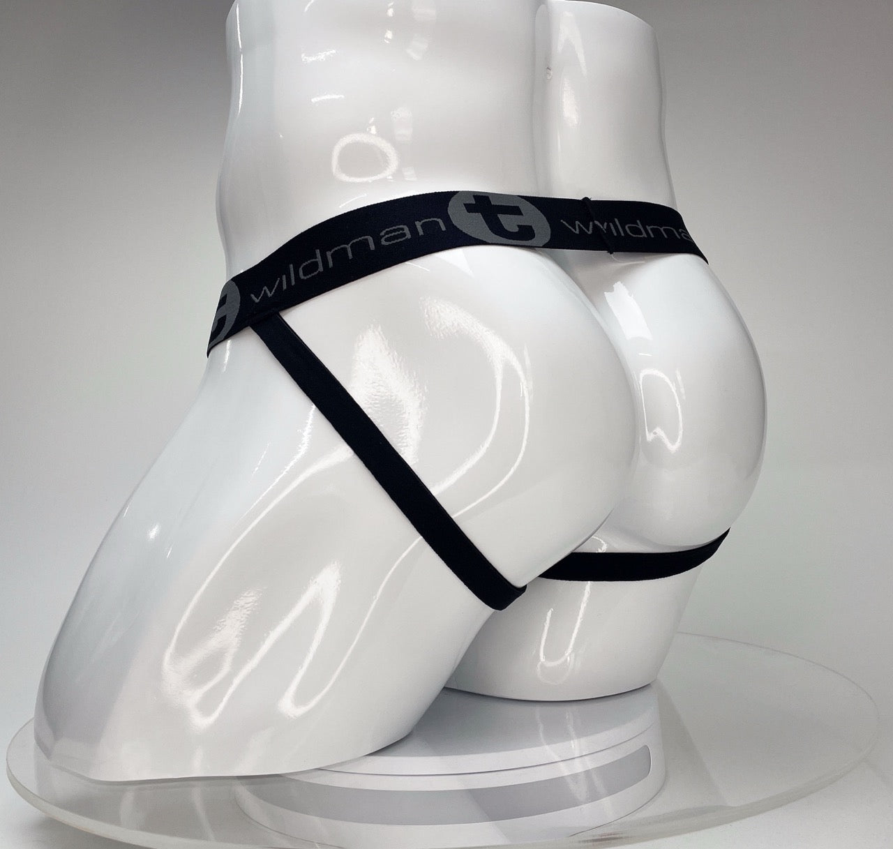 White jockstrap on a white mannequin torso, featuring a black waistband with the "WildmanT" logo in gray.
