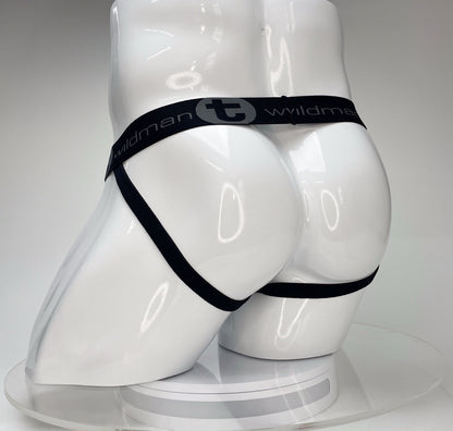 White jockstrap on a white mannequin featuring a black elastic waistband with "WildmanT" logo and leg straps.