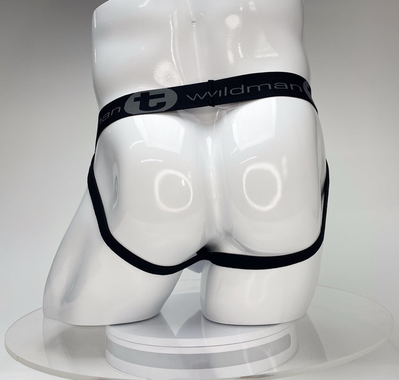 White WildmanT jockstrap on a white mannequin, featuring a black waistband with "WildmanT" logo and black leg straps.