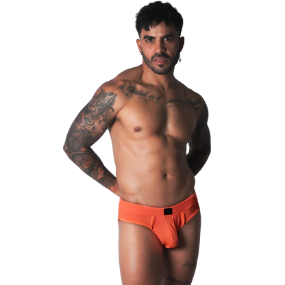 Bright orange athletic mesh jockstrap with a black logo patch on the center waistband, worn by a muscular man.