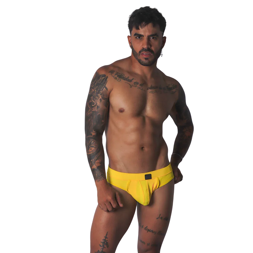Yellow textured fabric jockstrap with a central black tab detail on the waistband, worn by a tattooed man.