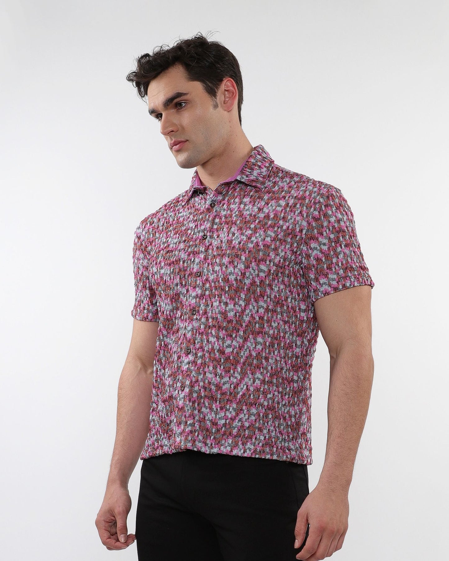 A man wearing a crinkle knit short sleeve shirt with a textured abstract pink and gray pattern