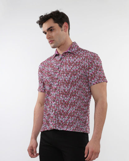 A man wearing a crinkle knit short sleeve shirt with a textured abstract pink and gray pattern