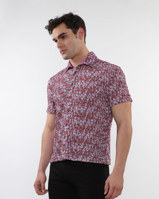 A man wearing a crinkle knit short sleeve shirt with a textured abstract pink and gray pattern