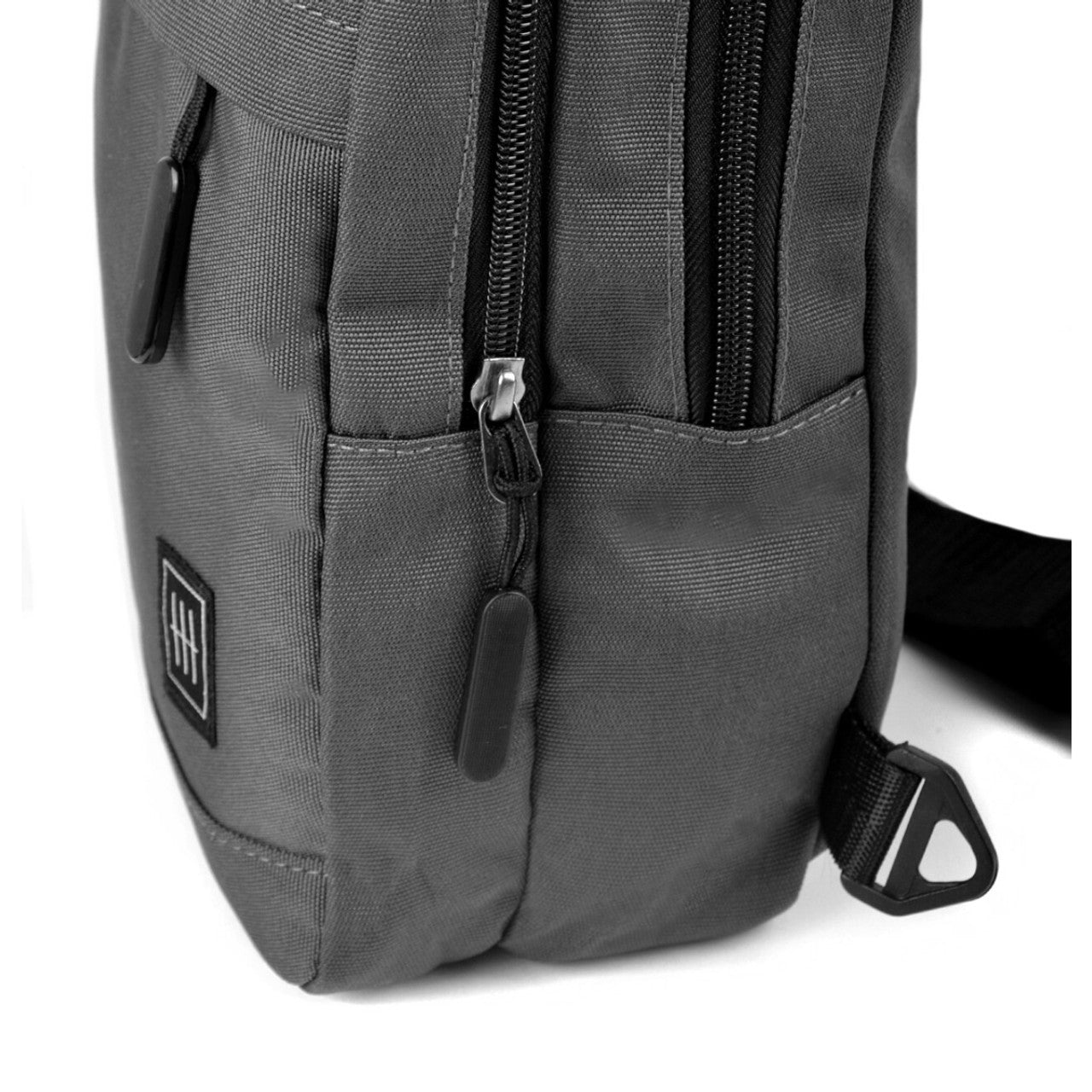 Dark gray canvas crossbody sling bag with black zippers and small square logo patch for everyday use