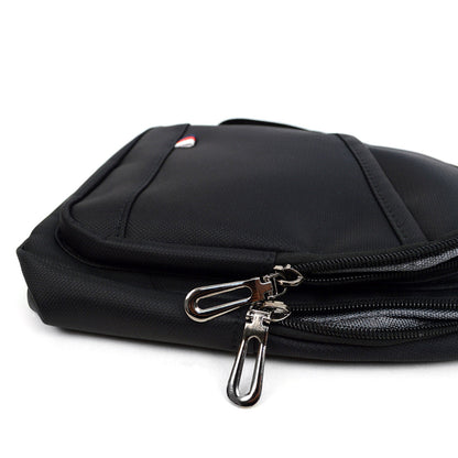 Black nylon crossbody sling bag with silver zipper pulls and small red white and blue logo on the front