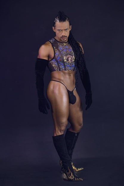 A man wearing a candyMan 99805 stained glass black print sheer patterned crop top with gold and blue designs