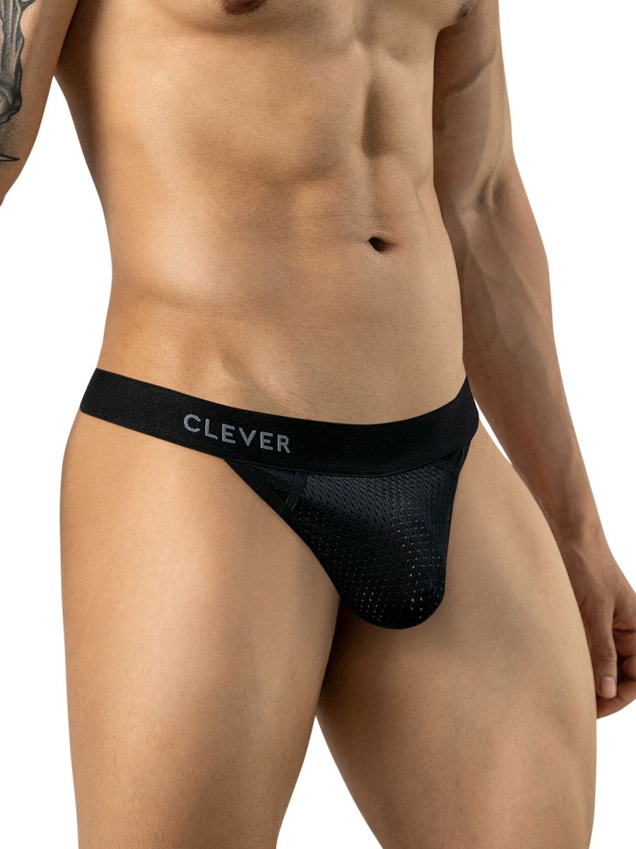 A man wears black mesh thong underwear featuring a branded elastic waistband in a frontal view.