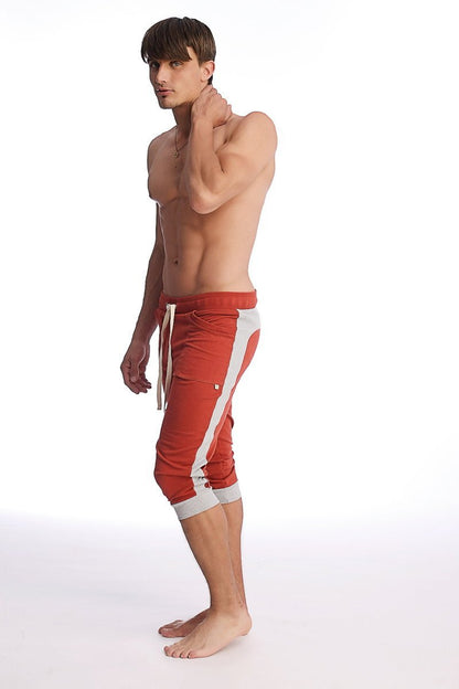 Cuffed yoga pants in cinnabar with grey featuring red athletic capri style, white side stripes, and matching drawstring waistband