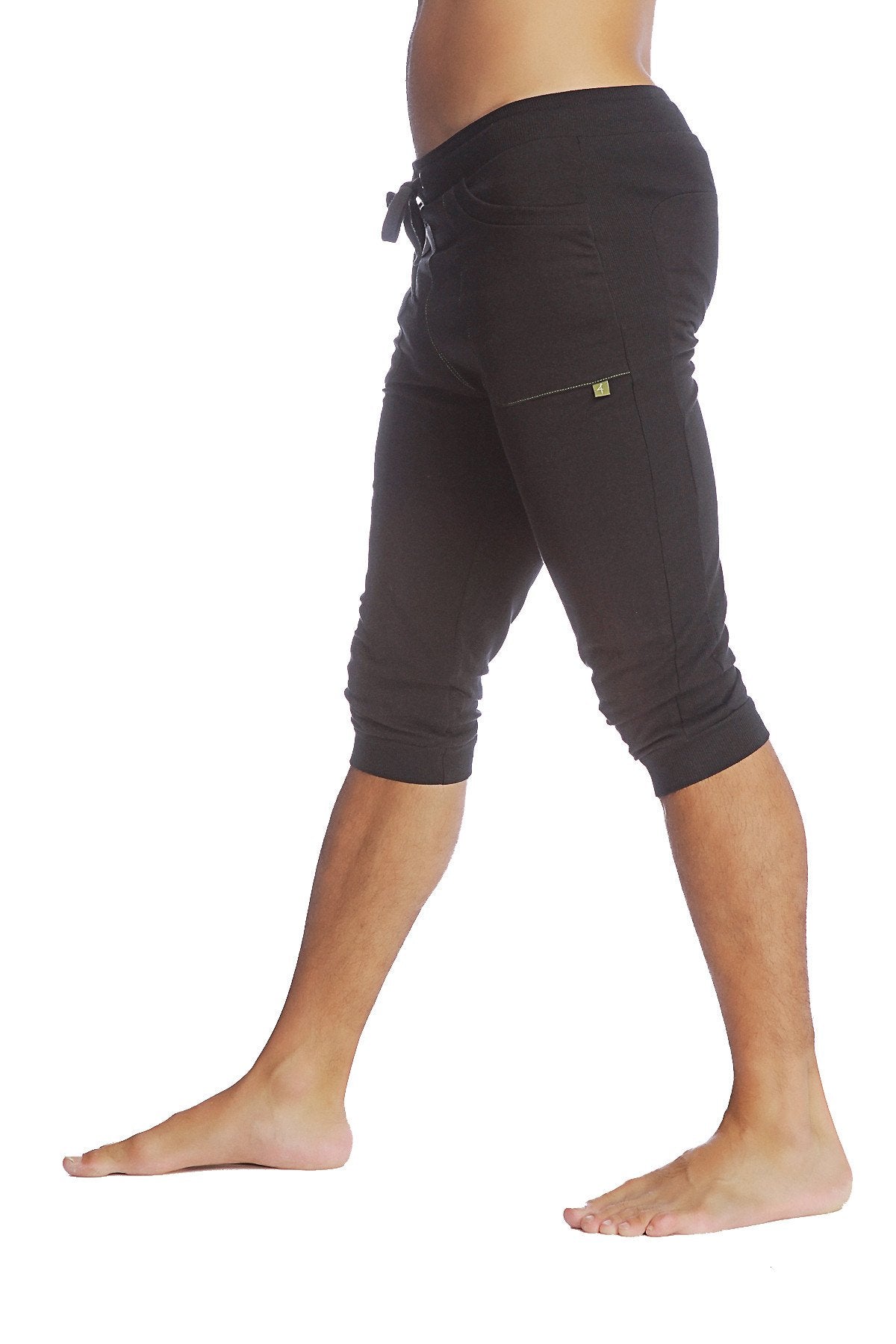 Black cuffed yoga pants with elastic waistband drawstring and yellow logo on thigh pocket in solid black fabric