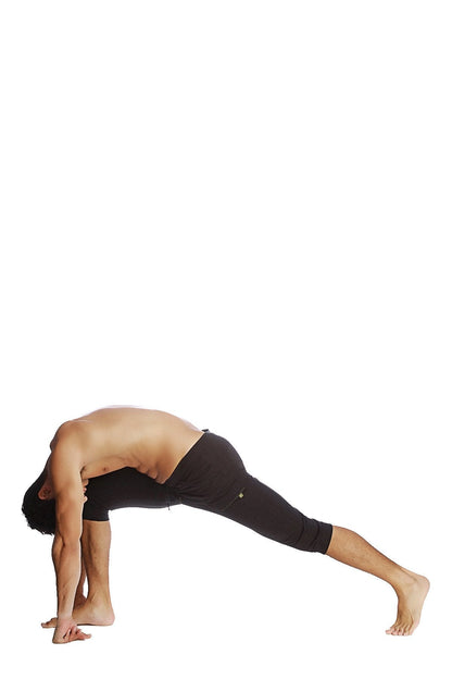 A man in solid black cuffed yoga pants made of stretchy material performs a yoga pose against a white background