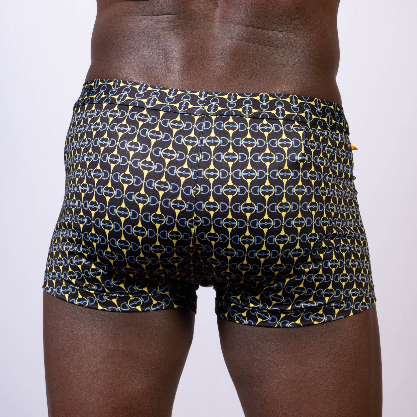 Black swim trunks with a bold yellow and blue chain-link buckle print designed for swimming and beachwear