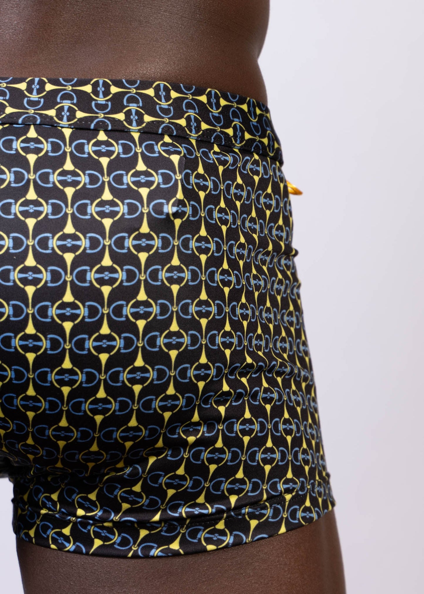 Black designer buckle print sq cut trunk swim trunks with bold yellow and light blue interlocking horseshoe logos