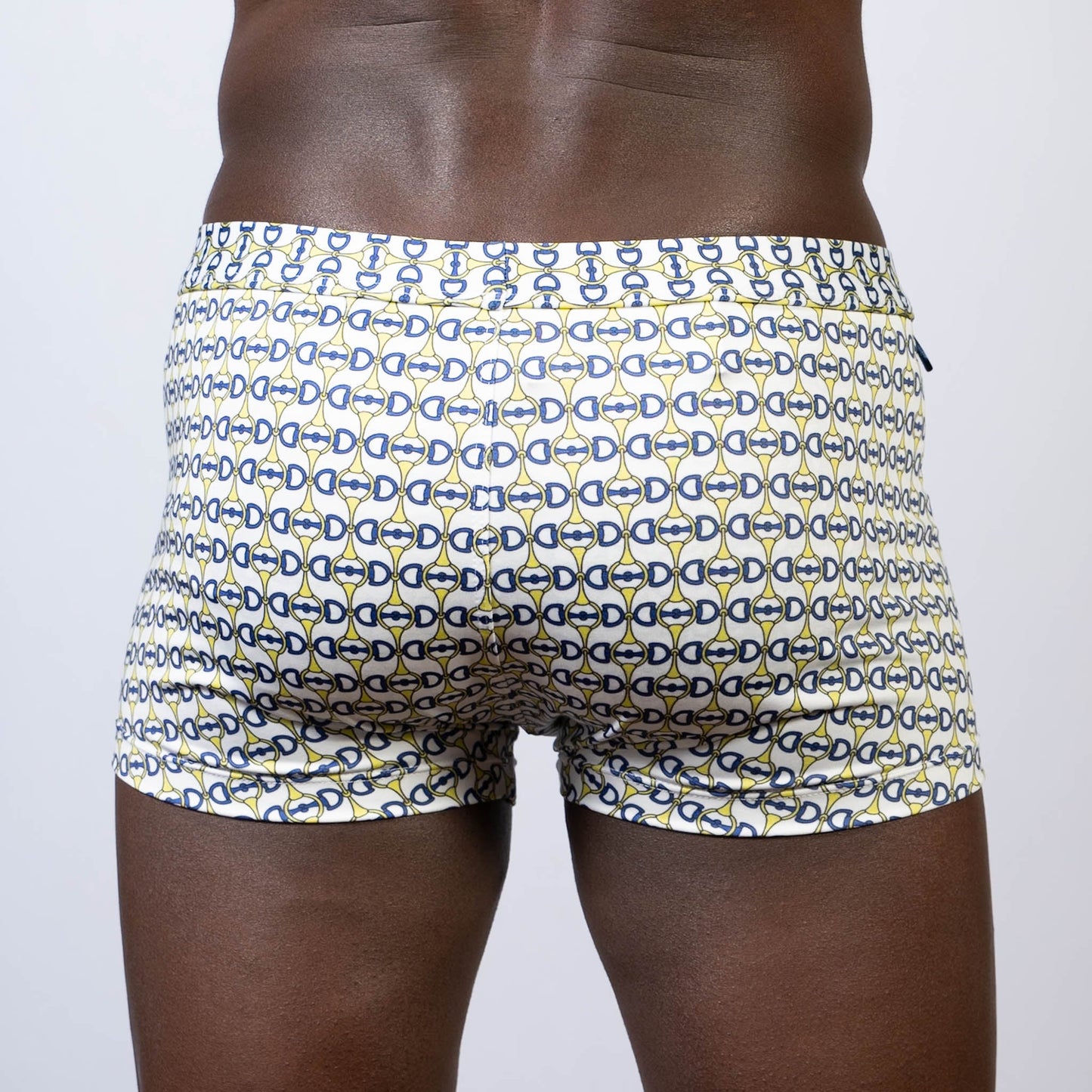 White designer buckle print sq cut swim trunks with navy blue and yellow interlocking d-shape pattern