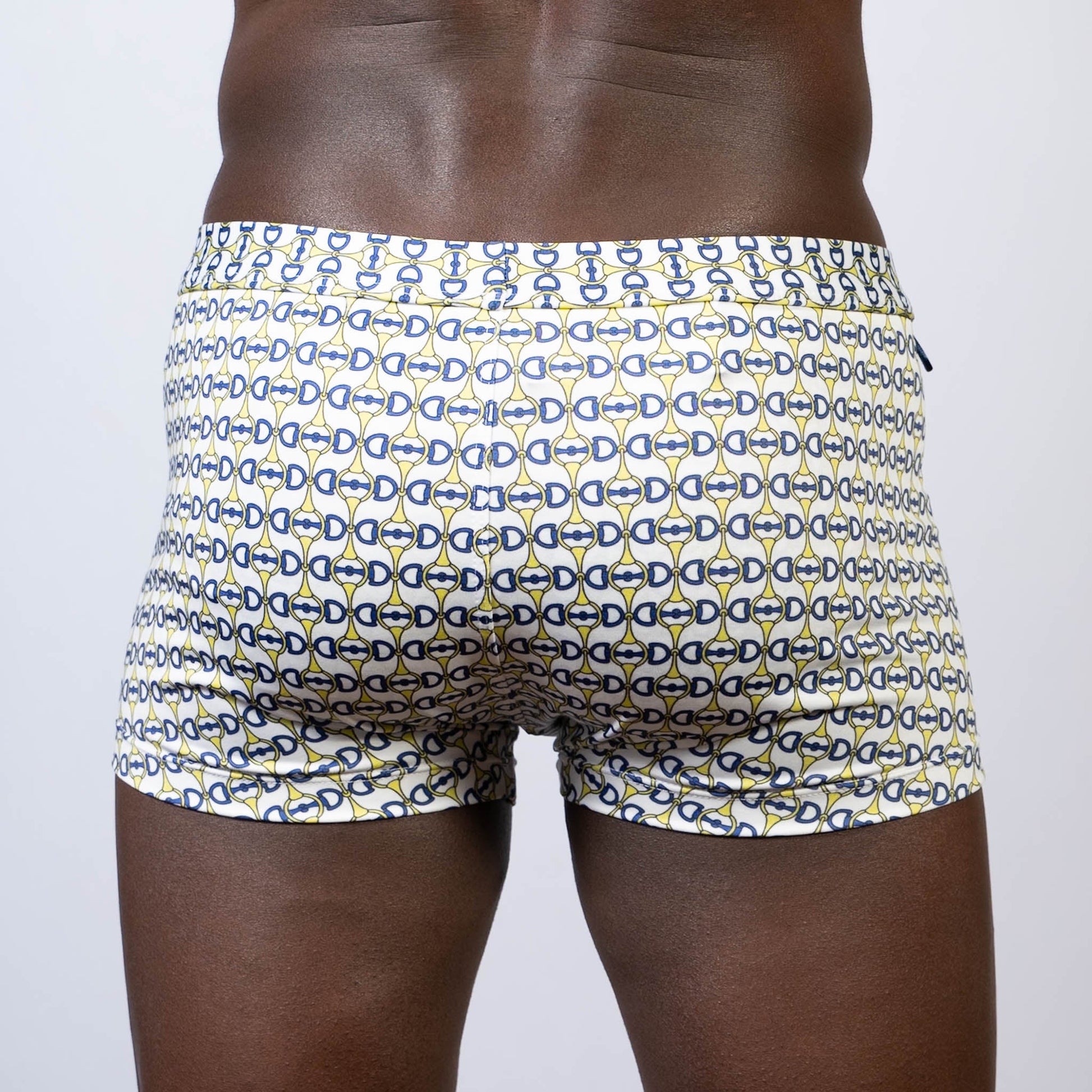 White designer buckle print sq cut swim trunks with navy blue and yellow interlocking d-shape pattern